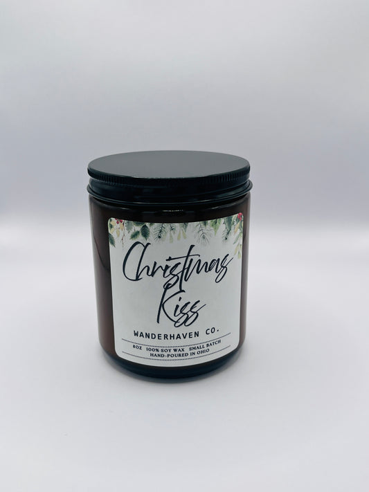 Candle jar labeled 'Christmas Kiss' by Wanderhaven Co. on a neutral background