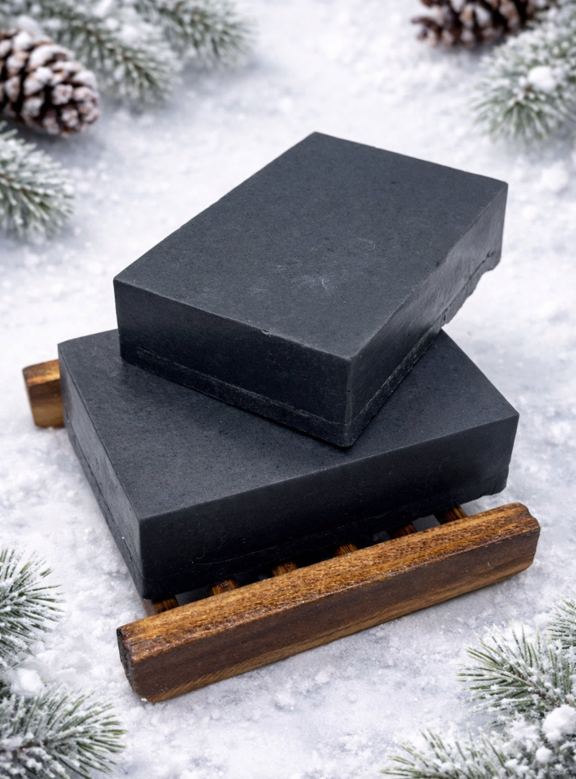 Two black soap bars on a wooden stand with a snowy background