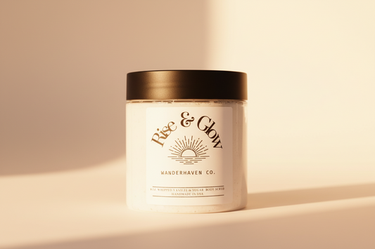 Rise and glow whipped body scrub container is clear showing white whipped sugar scrub. Sun hits the bottle for a sunrise effect. 